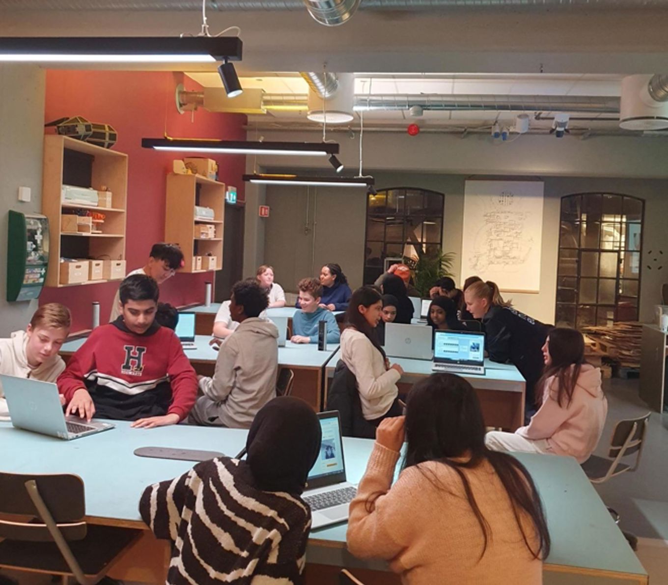 en gruppe mennesker som sitter ved bord med datamaskiner