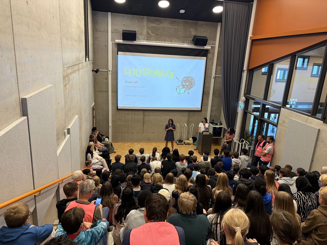 en gruppe mennesker som sitter i et rom med en stor skjerm